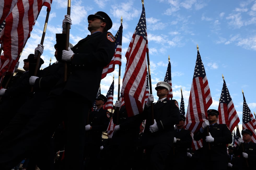 Miembros del Departamento de Bomberos de Nueva York marchan con banderas estadounidenses...